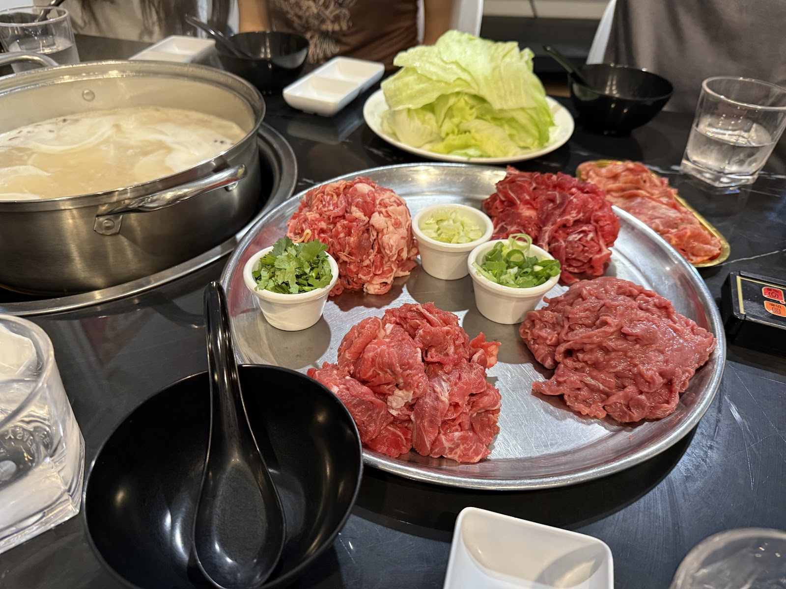 A full table spread with the beef platter, sauces, cabbage and the pot