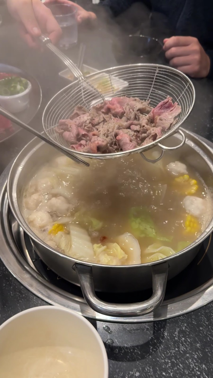 Steam rising as a scoop of beef comes out of the pot